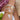 Close-up of a wrist wearing two bracelets with fruit-themed charms, one pearl and gold, the other gold and white.