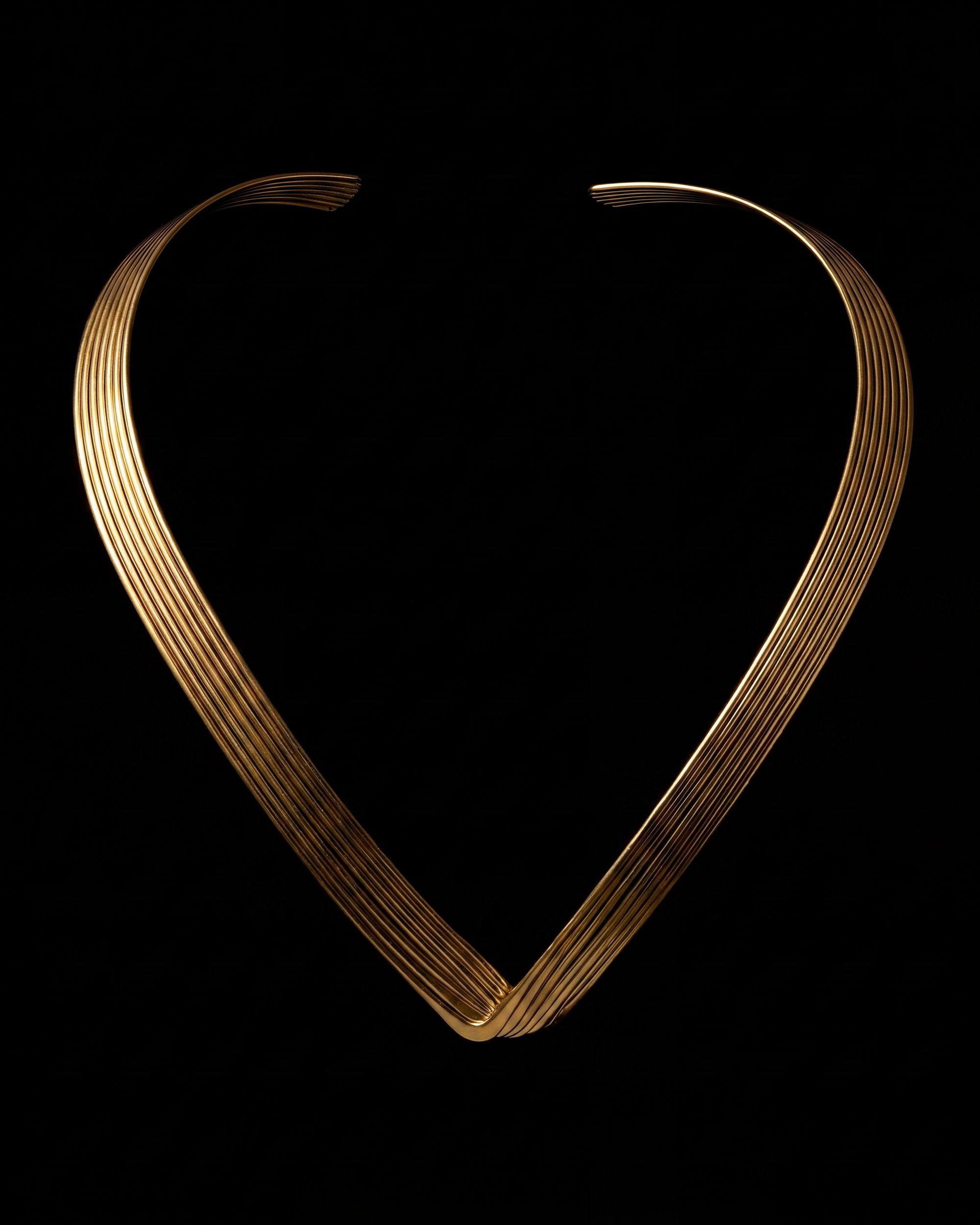 Gold necklace shaped like a heart on a black background