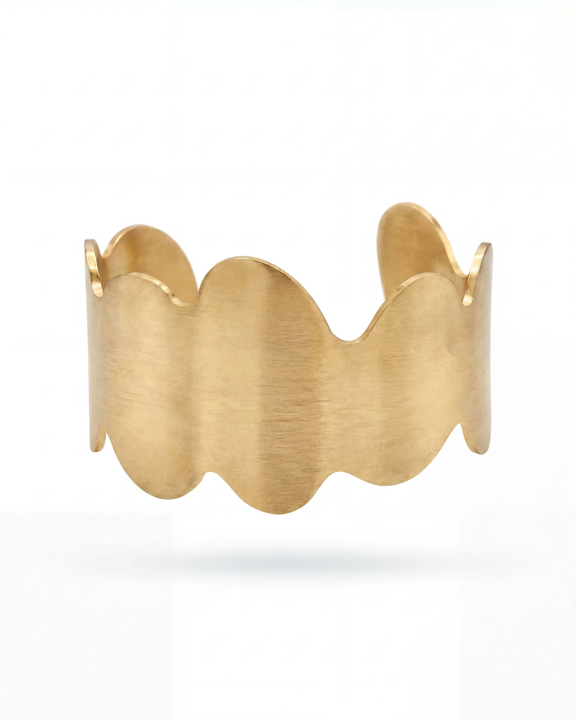 Gold bracelet with wavy design on a white background