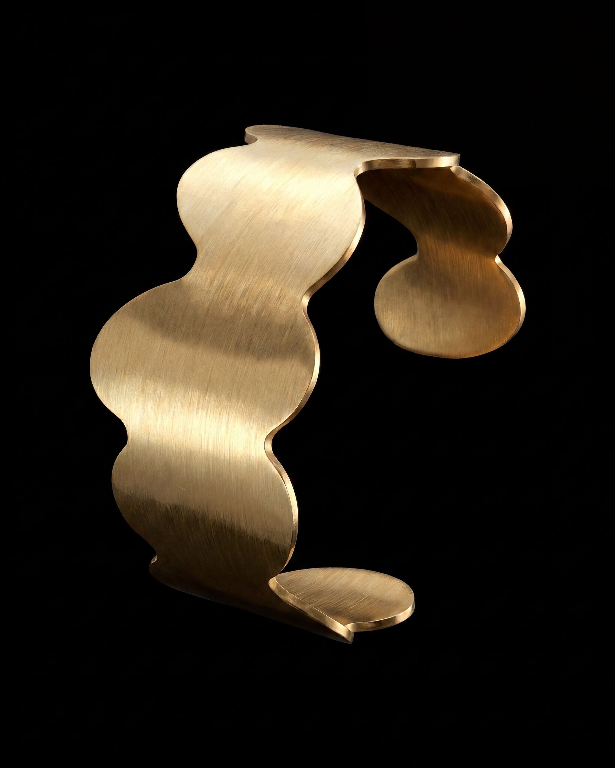 Gold bracelet with wavy design on a black background