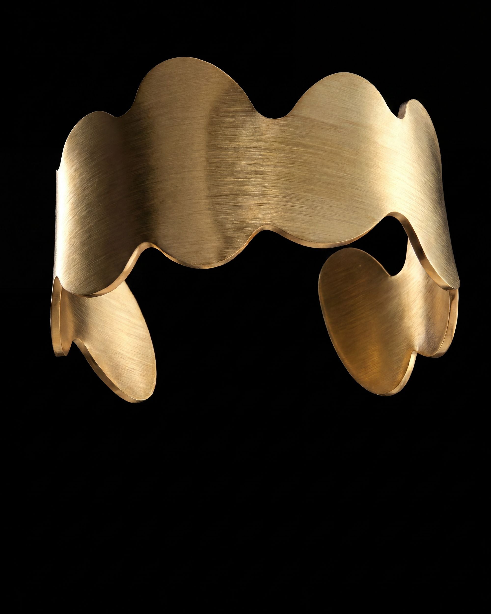 Gold bracelet with wavy design on a black background